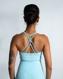 A person wearing a blue sports bra with a knotted back design.