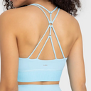 Back view of a woman wearing a light blue sports bra with an open, crisscross strappy back design. The brand name 'L3A' is printed in small gold letters on the lower back band.