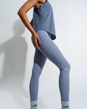 A pair of solid red leggings with a hidden pocket design, worn with a grey shirt and white sneakers.